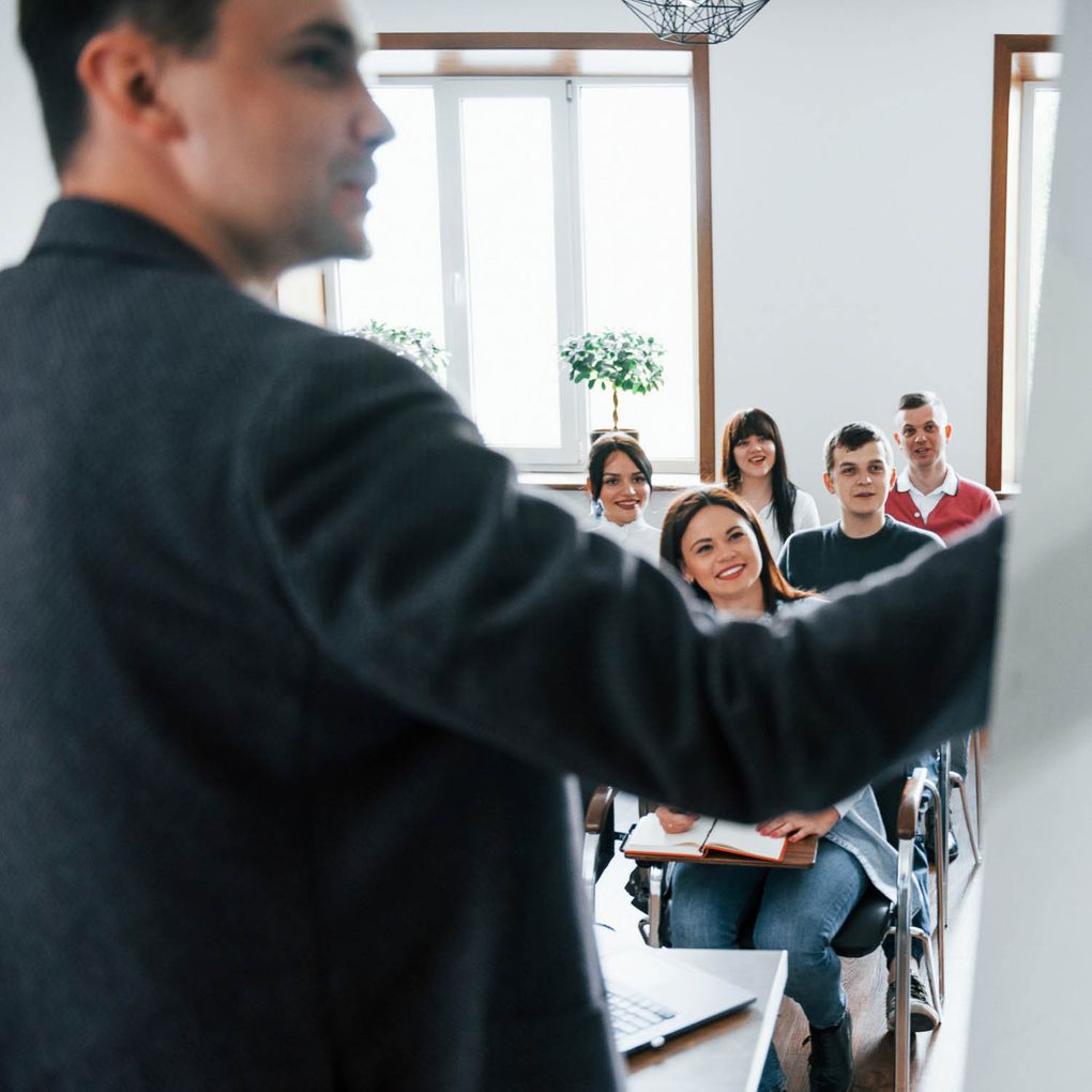 Lehrer präsentiert an einem Whiteboard vor seiner Klasse