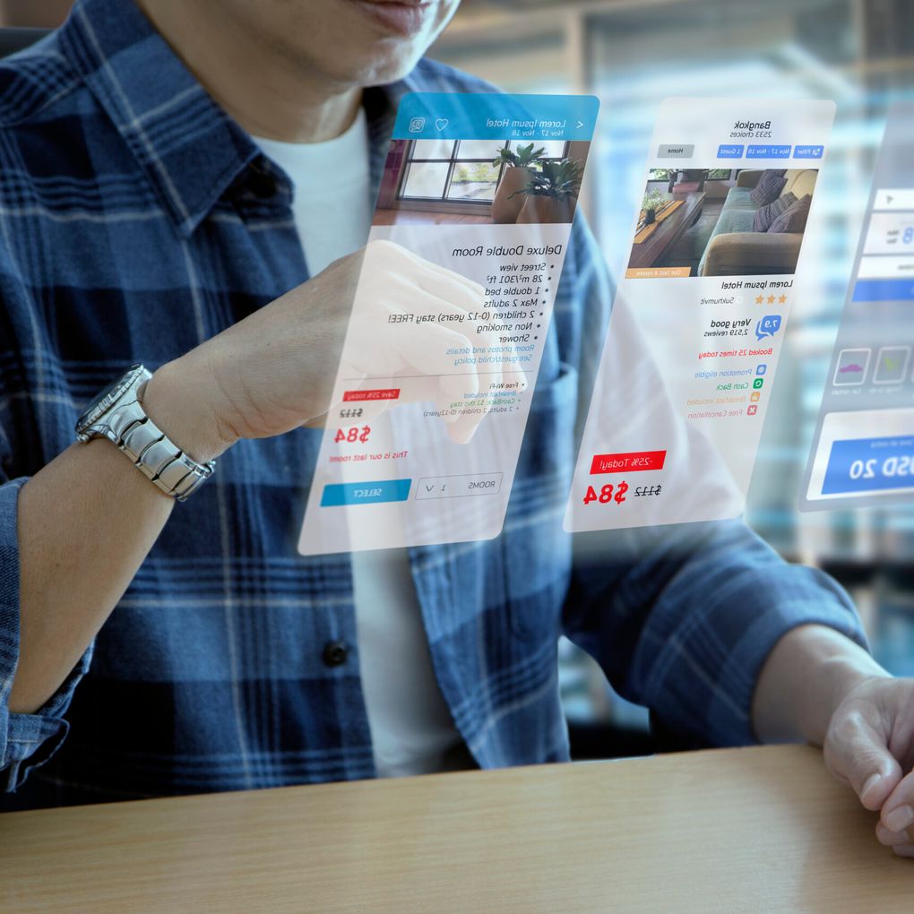 Mann in Freizeitkleidung bei der Interaktion mit einem futuristischen virtuellen Bildschirm einer Anwendung zur Hotelreservierung und Reiseplanung